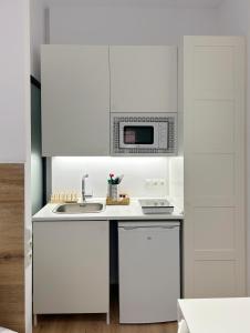 cocina blanca con microondas y fregadero en SD Habitación céntrica con baño y minicocina, en Terrassa