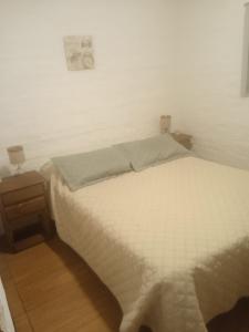 uma cama branca num quarto com uma parede branca em Estadía Nuestro Sueño em Colônia do Sacramento