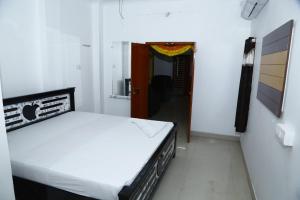 een slaapkamer met een bed en een deur naar een gang bij Sri Naari inn in Kondavīdu