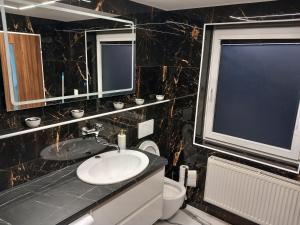 baño con lavabo y aseo y ventana en apartmánydelu en Blansko