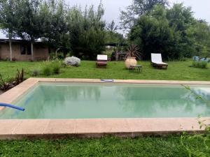 a swimming pool in the middle of a yard with two chairs at Casa Madre in Villa Yacanto