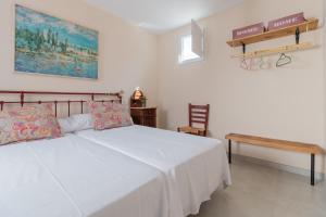 um quarto com uma cama branca e um banco de madeira em Luxury El Patio de la Judería em Córdoba