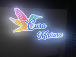 een neonbord met een kleurrijke vogel aan de muur bij Casa Maiana in Sámara