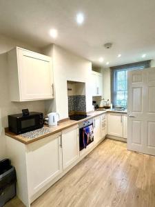 a kitchen with white cabinets and a black microwave at Curlew Cottage in Historic Rye in Rye