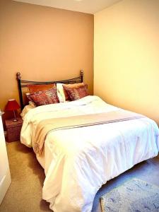 a bedroom with a bed with white sheets and pillows at Curlew Cottage in Historic Rye in Rye