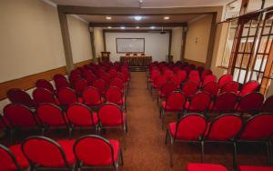 une salle de conférence vide avec des chaises rouges et un écran dans l'établissement Hotel Sol de Belén Cajamarca, à Cajamarca