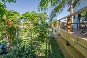 une terrasse couverte d'une maison avec une clôture et des arbres dans l'établissement Leu Jardin, à Saint-Leu