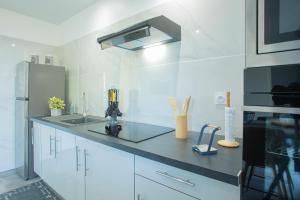 a white kitchen with a sink and a refrigerator at Leu Jardin in Saint-Leu