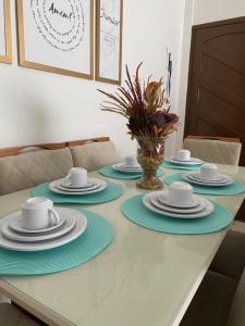 uma mesa com pratos e copos e um vaso em Apartamento na orla de Olinda em Olinda