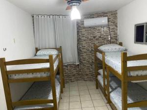 um quarto com 3 beliches e uma parede de tijolos em Apartamento na orla de Olinda em Olinda