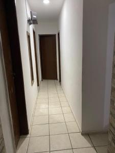um corredor com paredes brancas e piso em azulejo em Apartamento na orla de Olinda em Olinda