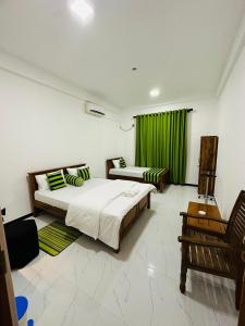1 dormitorio con 2 camas y cortina verde en Beach heaven villa, en Matara