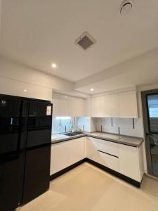 uma cozinha com armários brancos e um frigorífico preto em Luxurious 3-Bedroom in Hulhumalé em Hulhumale