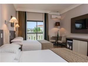 um quarto de hotel com três camas e uma televisão em Wish Foz do Iguaçu em Foz do Iguaçu
