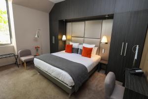 ブリーヴ・ラ・ガイヤルドにあるHôtel Château de Lacanのベッドルーム1室(大型ベッド1台、オレンジ色の枕付)