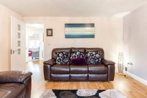 un sofá de cuero marrón en la sala de estar en Spacious 3-bed Home - Nature Reserve Retreat en Ince-in-Makerfield