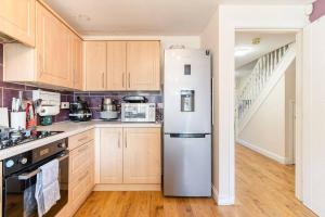 a white refrigerator in a kitchen with wooden cabinets at Spacious 3-bed Home - Nature Reserve Retreat in Ince-in-Makerfield