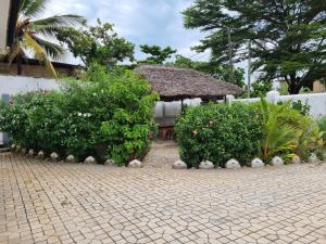 einen Garten mit Büschen und ein Gebäude mit Dach in der Unterkunft 64 ZENJ HOUSE Luxury Airport B&B in Mbweni