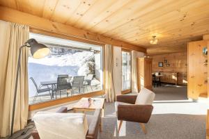 uma sala de estar com uma mesa e cadeiras e uma grande janela em Chasa Val Parterre em Scuol