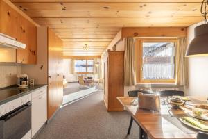 uma cozinha e sala de estar com tectos em madeira e uma mesa em Chasa Val Parterre em Scuol