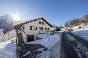 uma casa na neve com o sol atrás dela em Chasa Val Parterre em Scuol