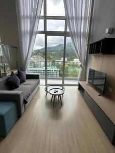 a living room with a couch and a table in front of a window at Windmill Upon Hills & Geo38 Genting in Genting Highlands