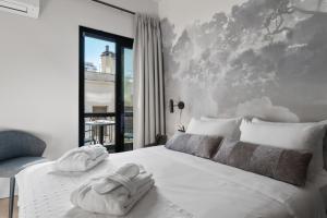 ein Schlafzimmer mit einem weißen Bett und Handtüchern darauf in der Unterkunft Azur Hotel Volos in Volos