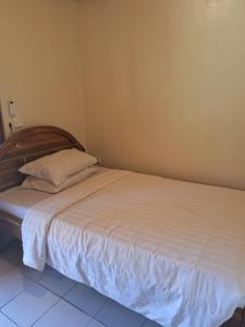 Schlafzimmer mit einem Bett mit weißer Bettwäsche und Kissen in der Unterkunft Gusti Home Stay Ubud in Ubud