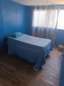 uma cama num quarto azul com uma janela em Casa yeici em Viña del Mar