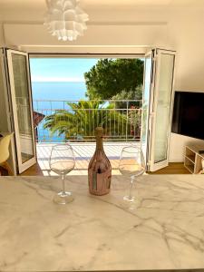 a bottle of wine sitting on a counter with two wine glasses at Botanic Garden Apartment Calandre Beach Ventimiglia in Ventimiglia