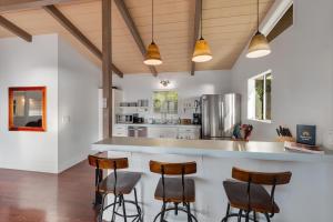 a kitchen with white walls and wooden ceilings and bar stools at Walua Trail Estate in Kailua-Kona