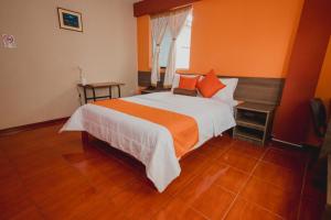 a bedroom with a large bed with an orange wall at Hotel Sol de Belén Cajamarca in Cajamarca