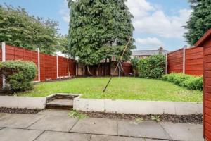 einen Hinterhof mit einem Zaun und einem Hof mit einer Schaukel in der Unterkunft Newly renovated house near Trafford Centre in Manchester