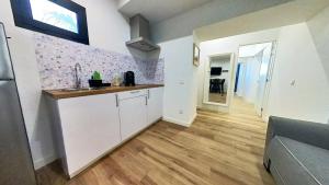 a kitchen with white cabinets and a wooden floor at MyHome Urban Apartments-Air Conditioning-City Center in Puerto del Rosario +126 photos
