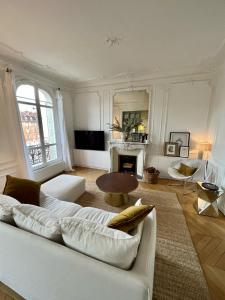 een woonkamer met een witte bank en een open haard bij Grand appartement Haussmannien à 12 min de Paris - Proche Stade de France - Jeux Olympiques 2024 in Enghien-les-Bains