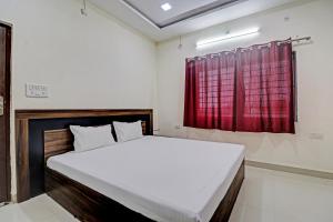 Dhār的住宿－Hotel Midway Treat Dhar，一间卧室配有一张带红色窗帘的大床