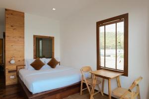 a bedroom with a bed and a table and a window at Akina Beach Resort KohLarn อกินะบีช รีสอร์ทเกาะล้าน in Ko Larn