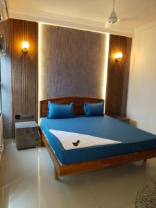 a bedroom with a bed with blue sheets and blue pillows at Hotel AK International - Chennai in Chennai