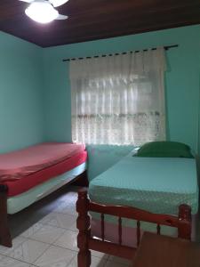Dos camas en una habitación con ventana. en Casa Curral, en Ilhabela