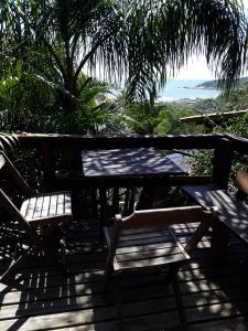 een picknicktafel en stoelen op een terras met uitzicht op de oceaan bij Pororoca_rosa in Imbituba