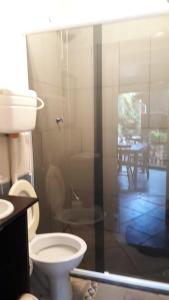 een badkamer met een toilet en een glazen douchedeur bij Pororoca_rosa in Imbituba