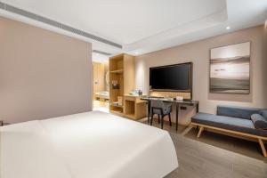 a bedroom with a bed and a desk and a tv at Atour Hotel Xi'an Chanba Exhibition Center Expo Park in Xi'an