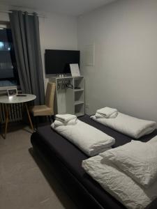 two beds in a room with a table and a tv at House Cologne in Cologne