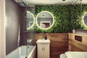 bagno con parete verde, lavandino e specchio di Elegance Loft Apartment a Skoczów