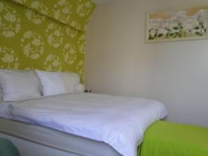 1 cama con sábanas blancas y almohadas en una habitación en B&B La Villa Zarin, en Bruselas