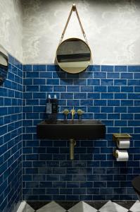 Baño de azulejos azules con lavabo negro y espejo en The Portico Hotel en Londres