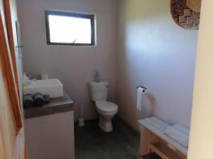 ein Badezimmer mit Toilette und Waschbecken und einem Fenster in der Unterkunft Bundu Camp in Heilbron