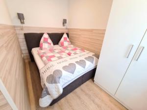 ein kleines Bett mit zwei Kissen darauf in einem Zimmer in der Unterkunft Ferienhaus Blütenzauber in Norddeich in Norddeich