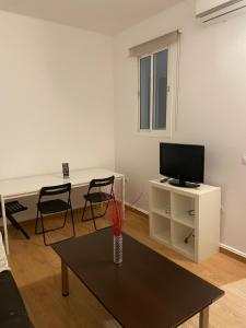 ein Wohnzimmer mit einem TV und einem Tisch mit Stühlen in der Unterkunft Arce apartamentos in Sevilla