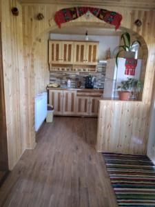 a kitchen with wooden cabinets and a refrigerator at Casa din Deal-Apuseni in Ocoale